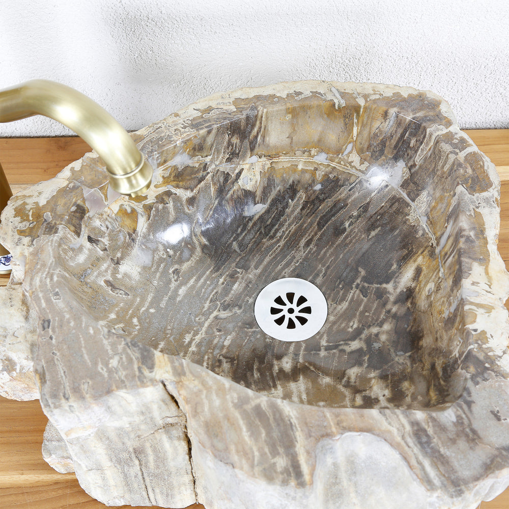 Handfat i natursten av fossilt trä med uttrycksfull ådring, invändig vy med avlopp och försiktigt slipad yta.