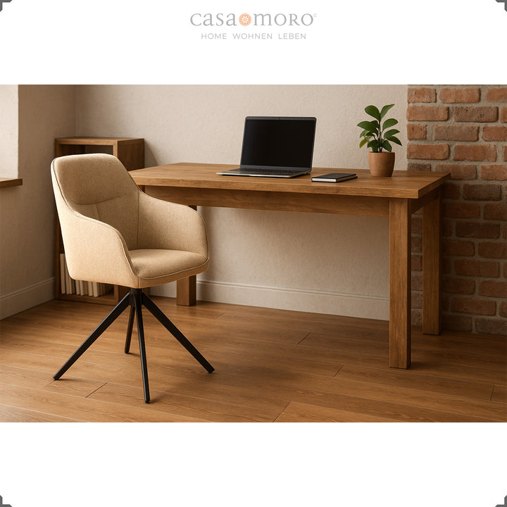 360° roterande klädd stol med armstöd i beige vid ett träbord med en bärbar dator, modern arbetsstation på hemmakontoret med varmt ljus och en tegelvägg