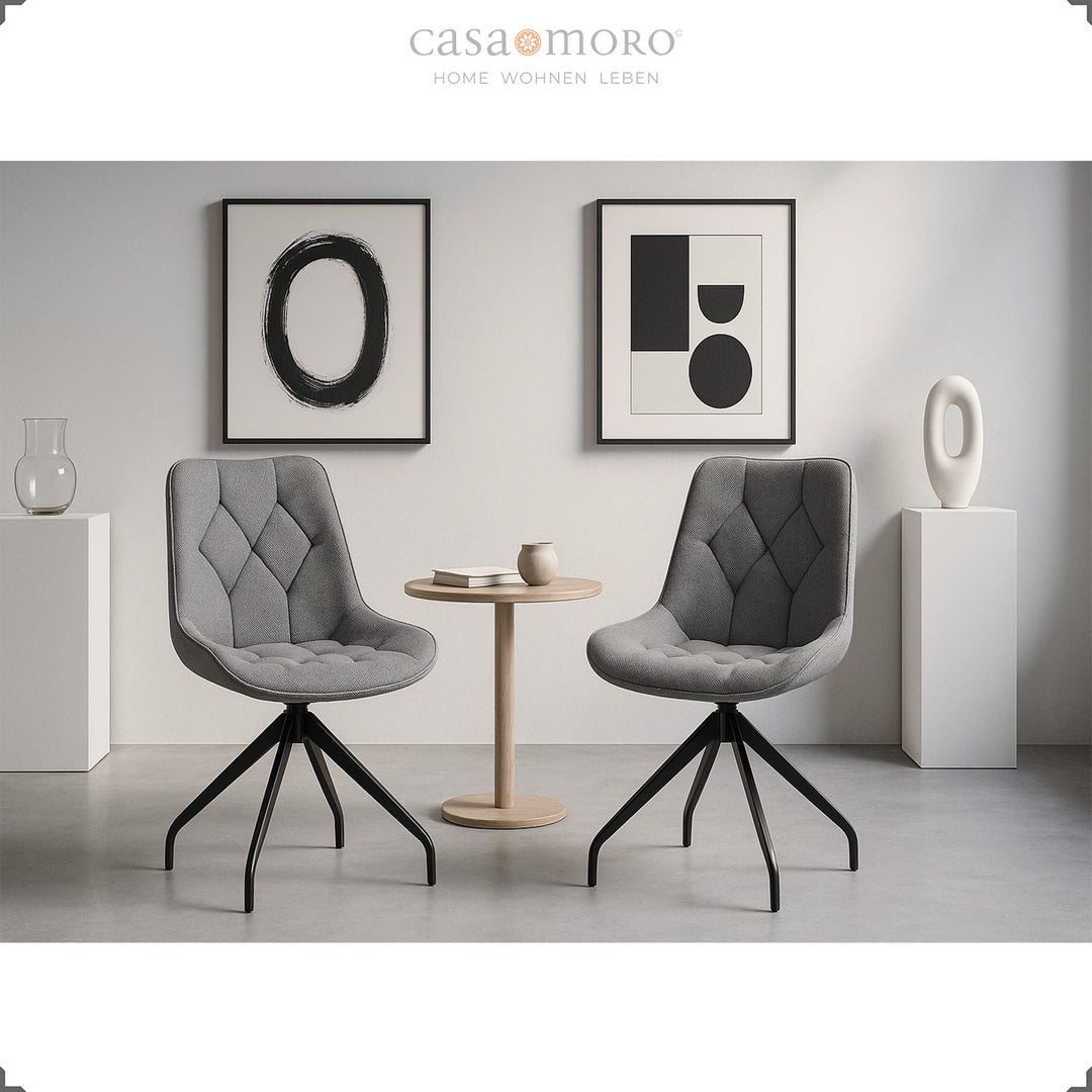 Två grå matsalsstolar med 360° vridfunktion och svart metallram - modern sittgrupp med sidobord och minimalistisk väggdekoration