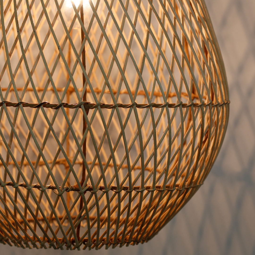 Detaljerad bild på en handgjord rottinglampa med ett fint, diagonalt vävmönster och varmt ljus