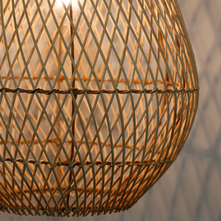 Detaljerad bild på en handgjord rottinglampa med ett fint, diagonalt vävmönster och varmt ljus