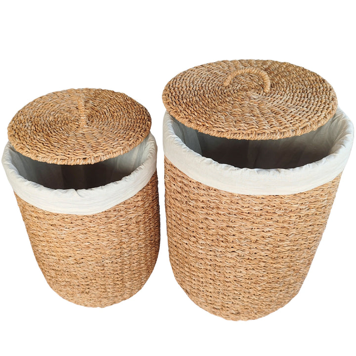 Wäschekörbe aus Seegras im 2er-Set S und M mit angehobenen Deckeln und sichtbaren hellen Wäschebeuteln.
